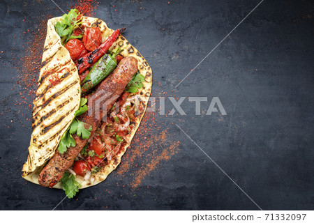 Traditional adana kebap skewer with tomato and salad  71332097