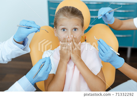 Scared girl with wide open eyes covers mouth with hands and sits in chair Scared girl with wide open eyes covers mouth with hands and sits in chair 71332292