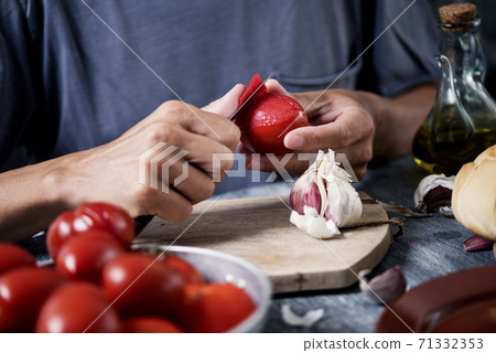 man peeling scalded tomatoes 71332353