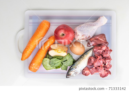 Overhead view of ingredients of barf raw food recipe for dogs consisting meat, organs, fish, eggs and vegetable on chopping board Overhead view of ingredients of barf raw food recipe for dogs consisting meat, organs, fish, eggs and vegetable on chopping board 71333142