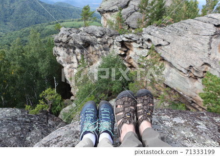 Male and female legs in trekking shoes on the top  71333199