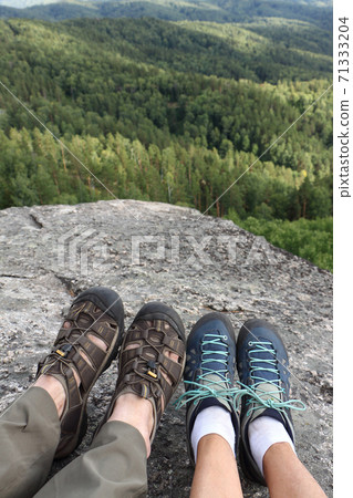 Male and female legs in trekking shoes on the top Male and female legs in trekking shoes on the top 71333204