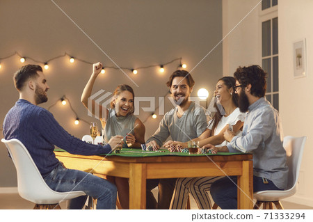 Smiling friends sitting and playing poker gambling at home 71333294