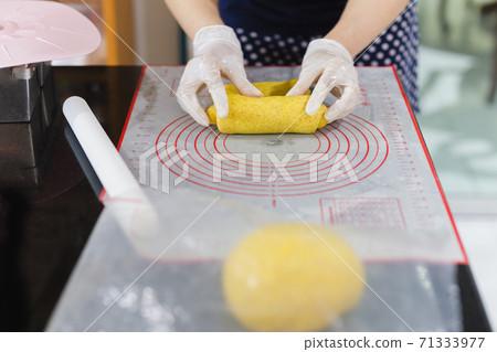 Womens hands roll out the pumpkin bread dough on kitchen table. Womens hands roll out the pumpkin bread dough on kitchen table. 71333977