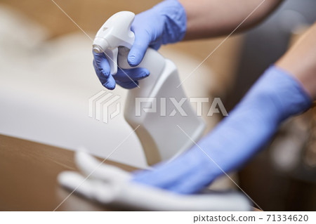 Maid disinfecting bedside table in the bedroom 71334620