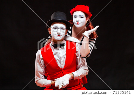 Portrait of two mime artists, isolated on black background. Woman appears from behind a man smiling. Symbol of happy marriage, sweet couple, love, family Portrait of two mime artists, isolated on black background. Woman appears from behind a man smiling. Symbol of happy marriage, sweet couple, love, family 71335141