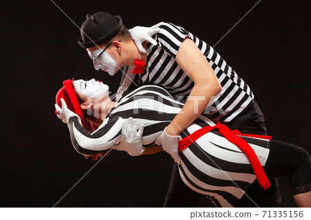 Portrait of two mime artists performing, isolated on black background. Man leaning his woman while dancing. Symbol of passion, pair dancing, embrace 71335156