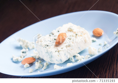 Blue cheese and almonds on plate on wooden background 71335193