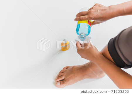 Woman pouring alcohol into a cotton for cleaning wound on her feet. Woman pouring alcohol into a cotton for cleaning wound on her feet. 71335203