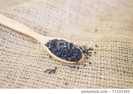 Black sesame seeds in wooden spoon pile 71335405