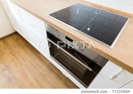 Modern cooking stove in white kitchen interior with tiled wall and wooden countertop 71335684