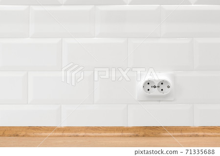 Socket in white kitchen interior with tiled wall and wooden countertop 71335688