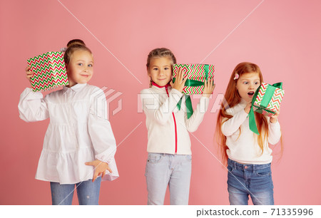 Giving and getting presents on Christmas holidays. Group of happy smiling children having fun isolated on pink studio background Giving and getting presents on Christmas holidays. Group of happy smiling children having fun isolated on pink studio background 71335996