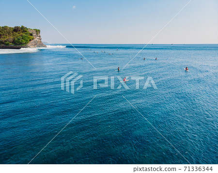Surfing waves in tropical ocean and cliff at background. Aerial view of island with waves Surfing waves in tropical ocean and cliff at background. Aerial view of island with waves 71336344