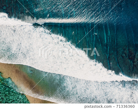 Aerial view of a surfers in blue ocean with waves. Top view Aerial view of a surfers in blue ocean with waves. Top view 71336360