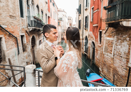 Gorgeous happy couple standing close to each other and looking in eyes in Venice, Italy 71336769