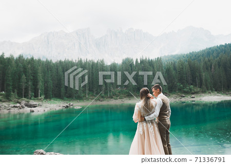 Beautiful modern couple near a lake in the mountains make wedding photos Beautiful modern couple near a lake in the mountains make wedding photos 71336791