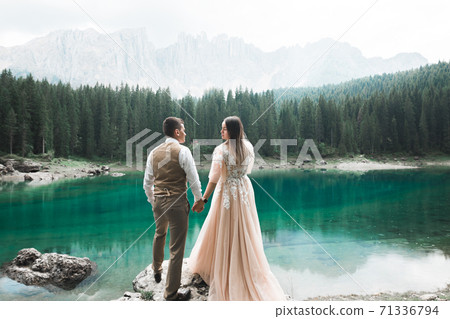 Young couple near lake Karersee, Italy. Holding hands at the stone at lake 71336794
