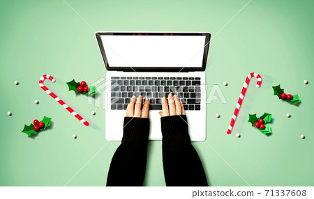 Person using a laptop computer with Christmas decorations 71337608
