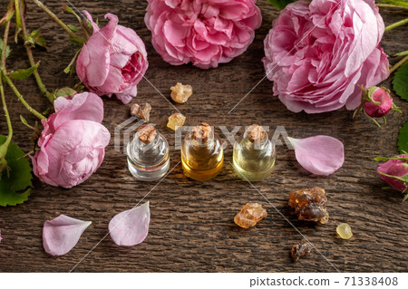 Essential oil bottles with frankincense resin and rose de mai flowers 71338408
