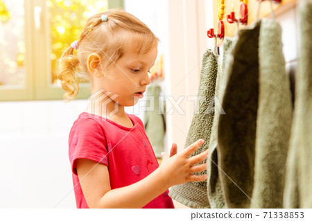 Little girl in nursery school using towel in bathroom Little girl in nursery school using towel in bathroom 71338853