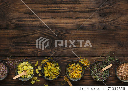 Row of bowls with dry medicinal herbs on brown wooden board. Top view, flat lay. Alternative medicine. Row of bowls with dry medicinal herbs on brown wooden board. Top view, flat lay. Alternative medicine. 71339856