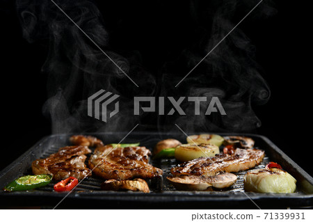 Hot Korean meat food preparation charcoal cooked with steam smoke bbq and vegetables on black background 71339931