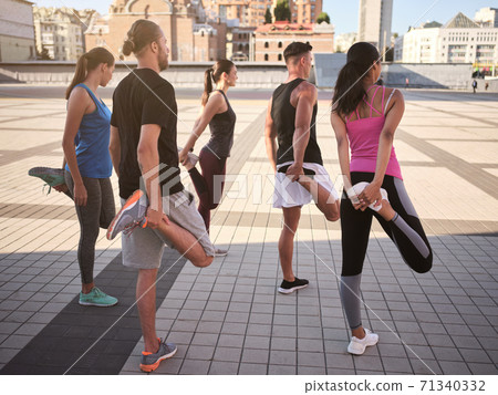 Rear view of young sportive people stretching legs Rear view of young sportive people stretching legs 71340332