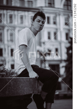 Guy sitting on the city street, look camera and around Guy sitting on the city street, look camera and around 71341292