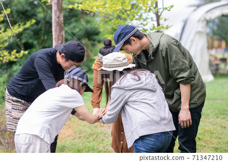 Asian men and women forming a circle with friends and colleagues at an outdoor such as a campsite 71347210