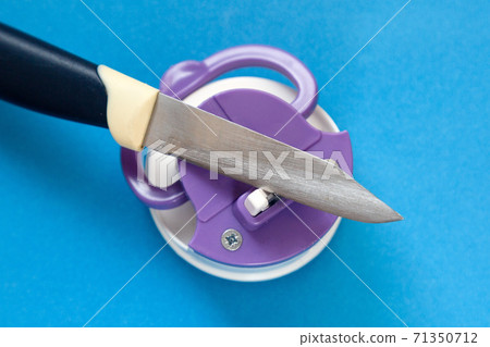 Kitchen knife and compact knife sharpener on blue background 71350712