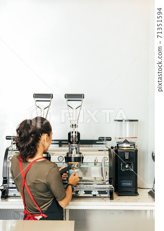Back view of a female barista making coffee. Woman in apron working in a small coffee shop. 71351594