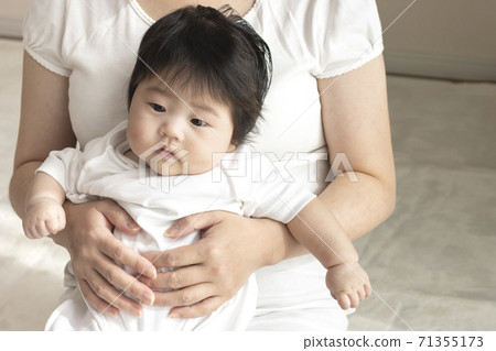 Mother in her 30s and baby sitting on her lap, 0 years old, 4 months old, girl Mother in her 30s and baby sitting on her lap, 0 years old, 4 months old, girl 71355173