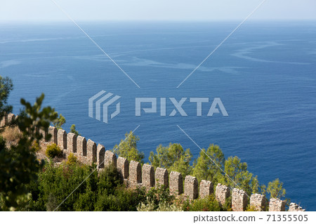 Old fortress stone wall on blue sea background. Old fortress stone wall on blue sea background. 71355505