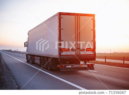 A truck with a trailer carries a groupage cargo on the highway against the backdrop of sunset. Concept of classification of transported goods, logistics, cargo handling 71356087