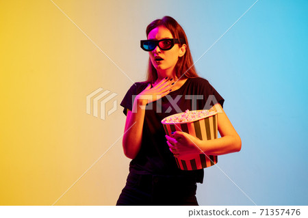 Young caucasian woman's portrait on gradient blue-yellow studio background in neon light 71357476