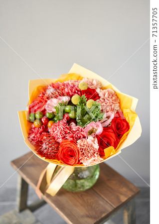 Red and green flowers. Autumn bouquet of mixed flowers in glass vase on wooden table. The work of the florist at a flower shop. Fresh cut flower. Red and green flowers. Autumn bouquet of mixed flowers in glass vase on wooden table. The work of the florist at a flower shop. Fresh cut flower. 71357705