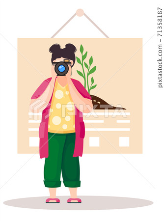 Girl standing and adjusting the lens. Photographer with poster with a planted tree on background Girl standing and adjusting the lens. Photographer with poster with a planted tree on background 71358187