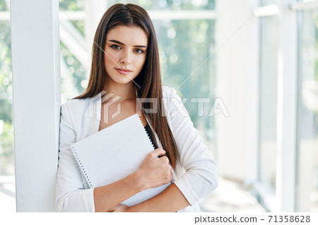 Confident business woman holding documents and looking at camera in modern creative office 71358628