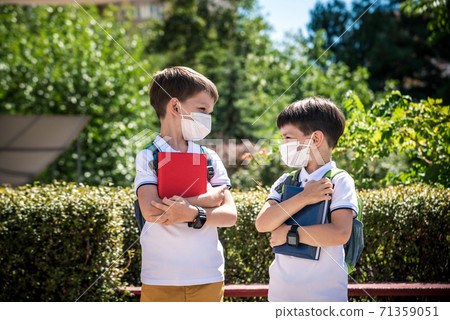 two boys, schoolchildren in black school uniforms with backpacks in a medical mask go to school independently, hold hands, friendship concept, study concept during coronavirus, back to school two boys, schoolchildren in black school uniforms with backpacks in a medical mask go to school independently, hold hands, friendship concept, study concept during coronavirus, back to school 71359051