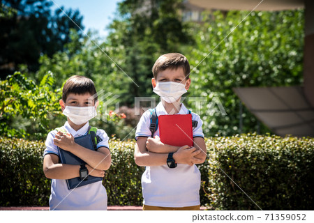 two boys, schoolchildren in black school uniforms with backpacks in a medical mask go to school independently, hold hands, friendship concept, study concept during coronavirus, back to school two boys, schoolchildren in black school uniforms with backpacks in a medical mask go to school independently, hold hands, friendship concept, study concept during coronavirus, back to school 71359052