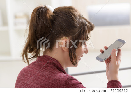 Deaf woman using smartphone 71359212