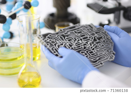 Man in gloves holds gearbox from car next to flasks of oil. 71360138