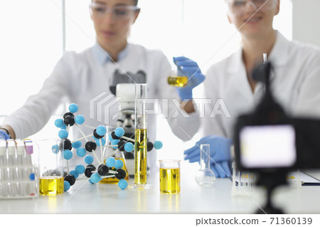 Scientists at work table on which flasks and molecules are filming experiments on video camera 71360139