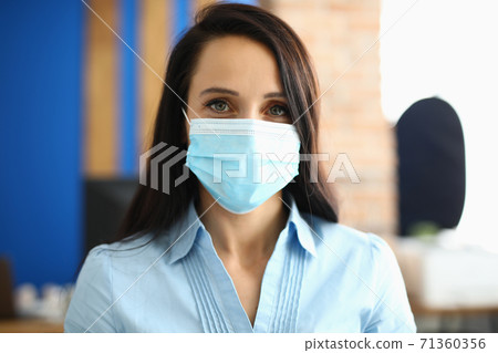 Portrait of businesswoman in protective medical mask in office 71360356