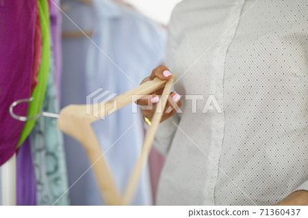 In female hand clothes hanger on background of clothes. In female hand clothes hanger on background of clothes. 71360437