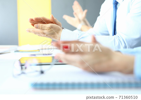 Womens and mens applaud at work table in office. 71360510
