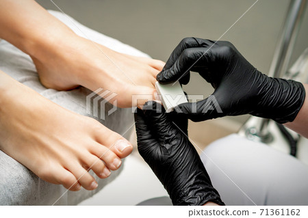 Pedicurist buffing toenail of woman Pedicurist buffing toenail of woman 71361162