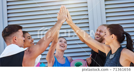Happy mixed race sport team giving high five near wall Happy mixed race sport team giving high five near wall 71361656