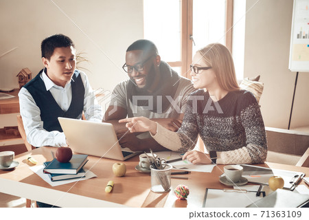 Woman smiles while showing men something in laptop Woman smiles while showing men something in laptop 71363109